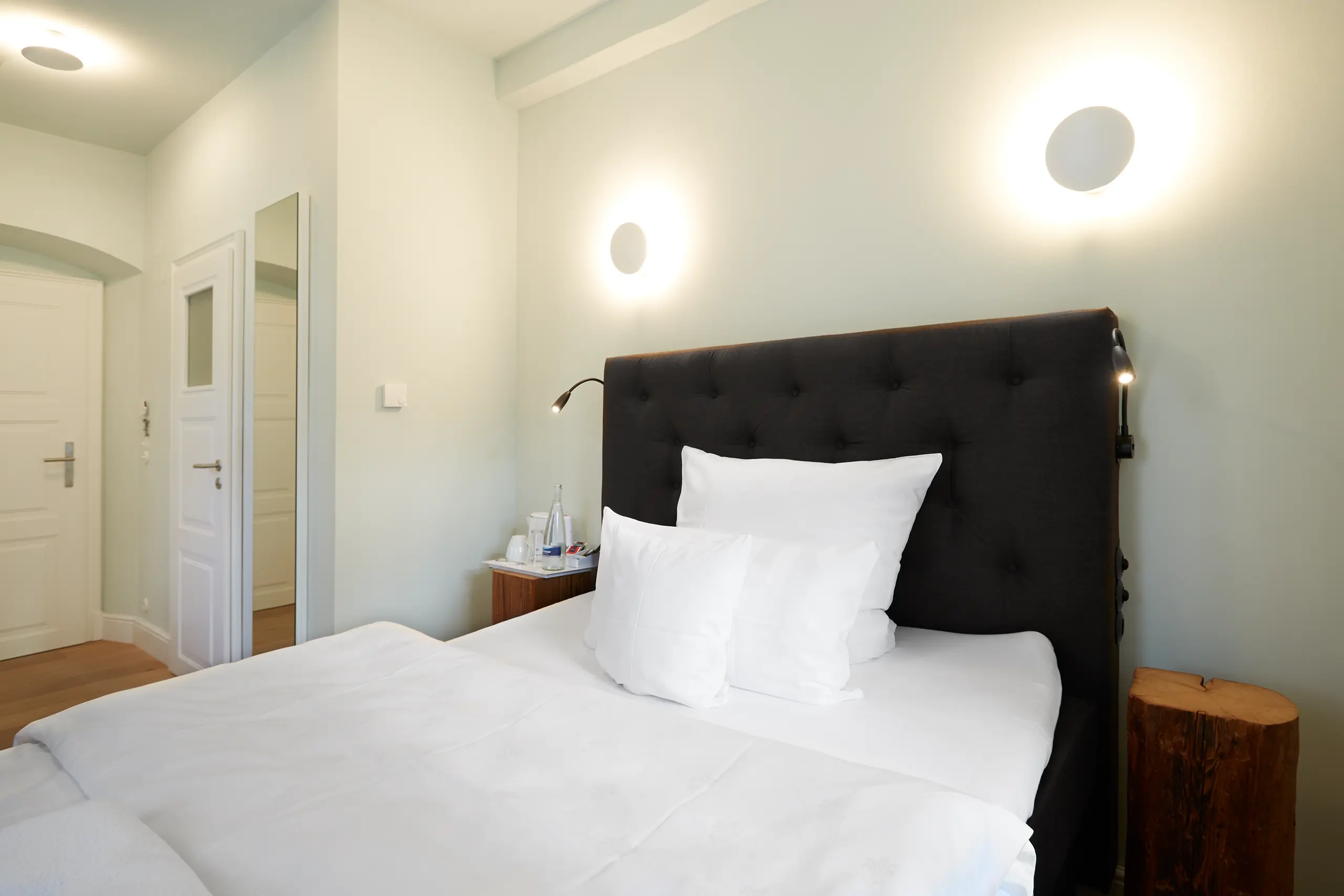 Standard-Zimmer 1 im Fachwerkhaus mit Doppelbett, Wandleuchten und Blick zur Tür