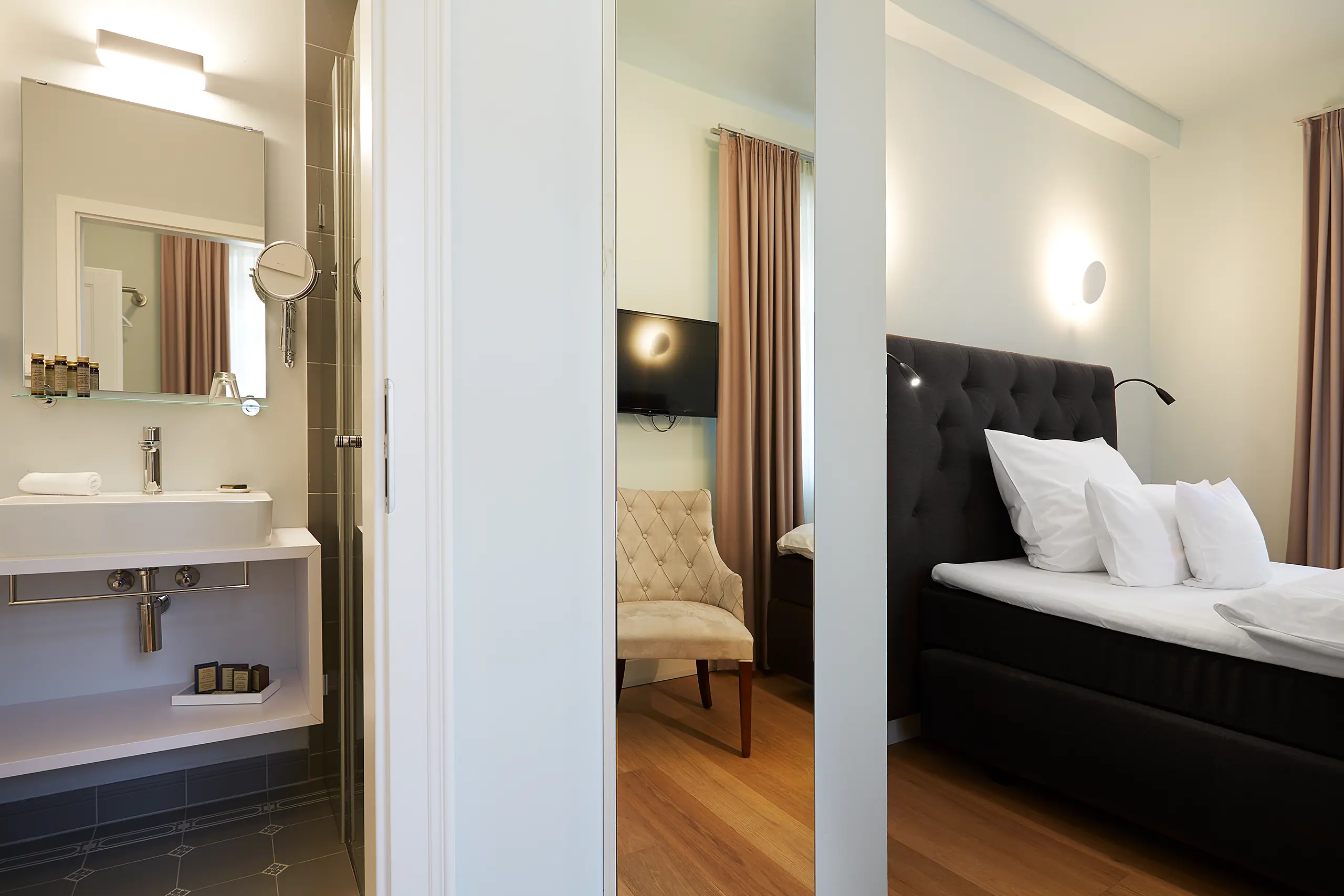 Blick vom Bad ins Standard-Zimmer 1 im Fachwerkhaus mit Doppelbett und Spiegel