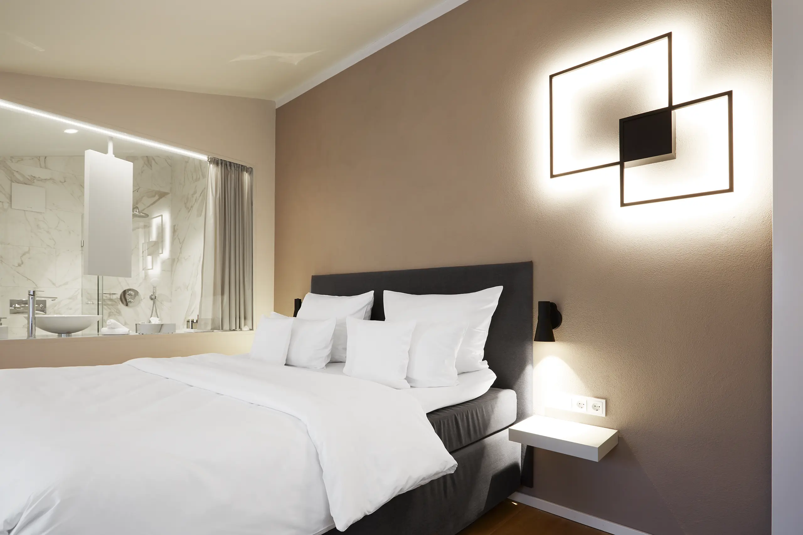 Doppelbett mit geometrischer Wandleuchte in der Honeymoon-Suite