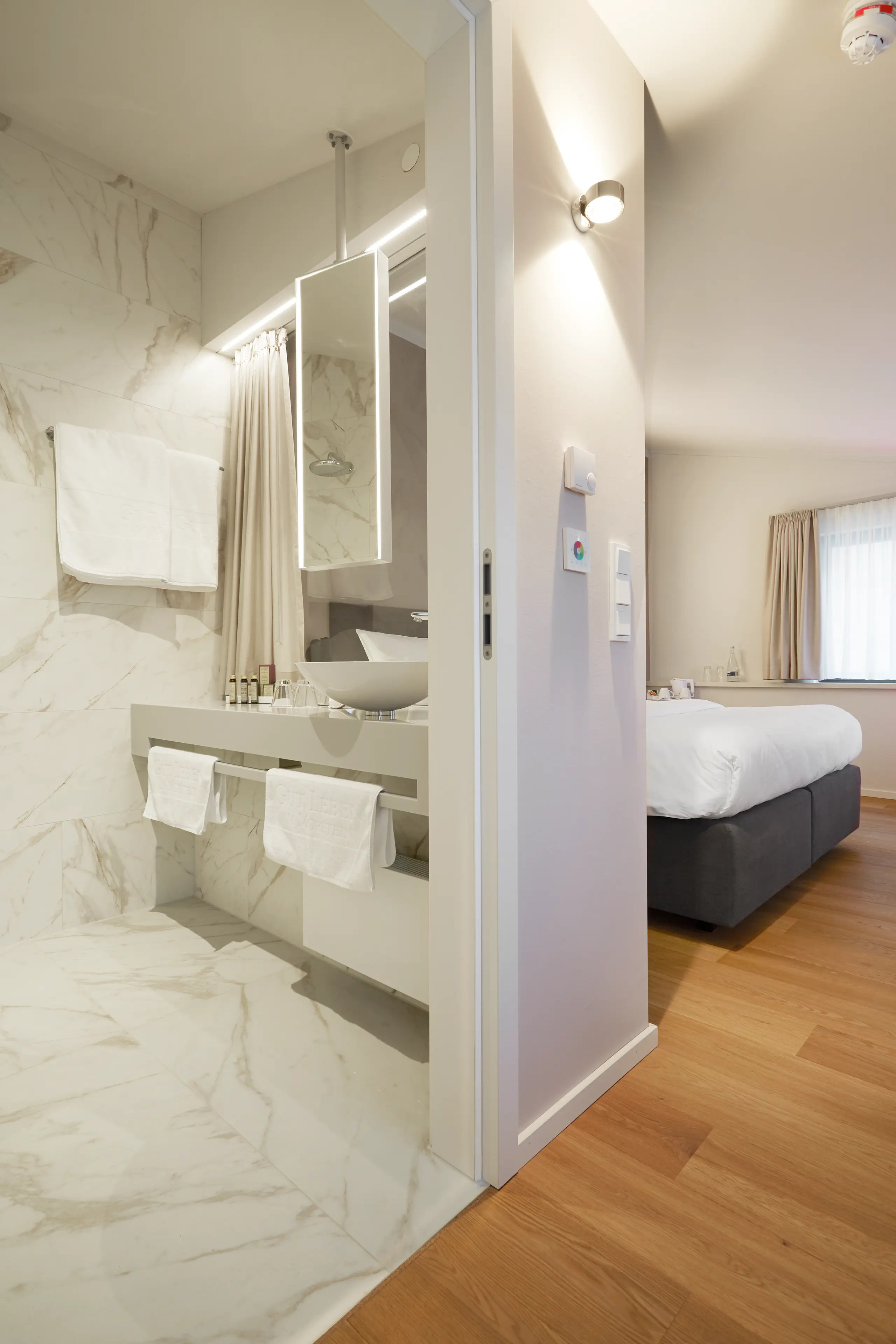 Blick vom Bad mit Marmorwand ins Schlafzimmer der Honeymoon-Suite