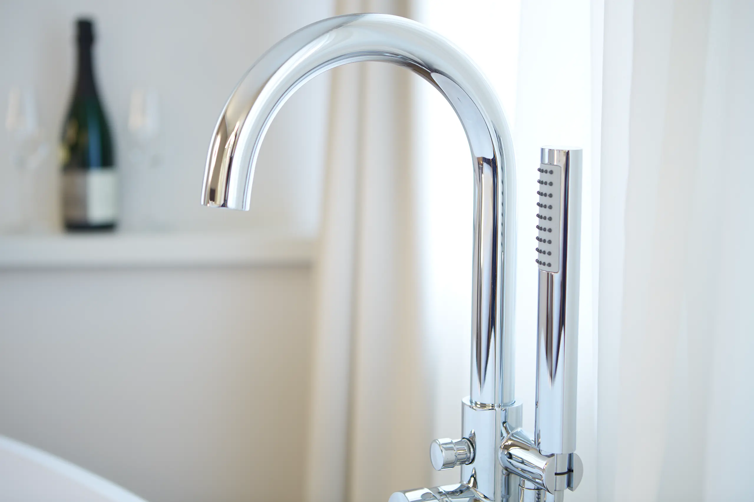 Chromarmatur der freistehenden Badewanne mit Weinflasche am Fenster in der Honeymoon-Suite