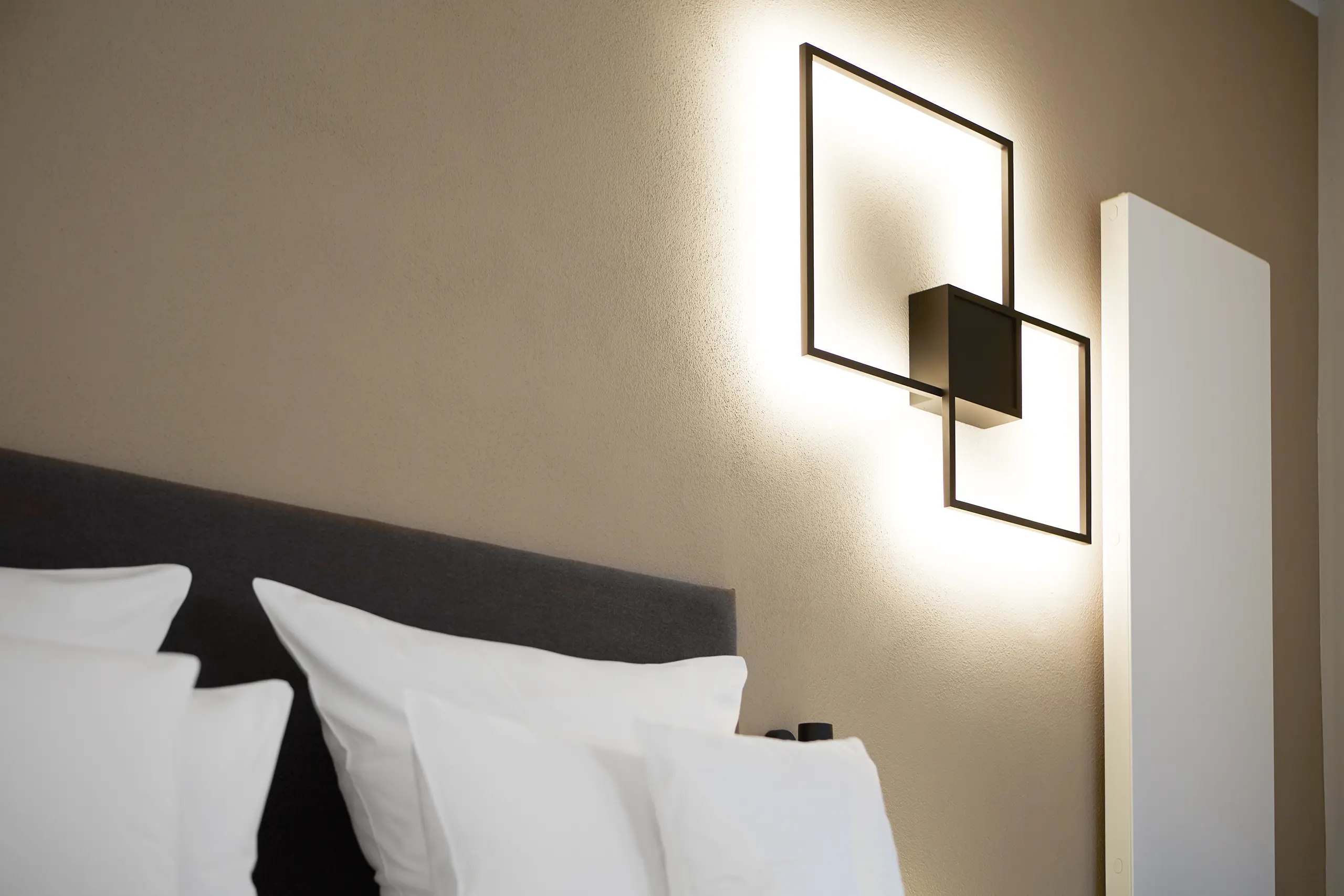 Kissen und Wandleuchte am Kopfteil des Betts in der Honeymoon-Suite