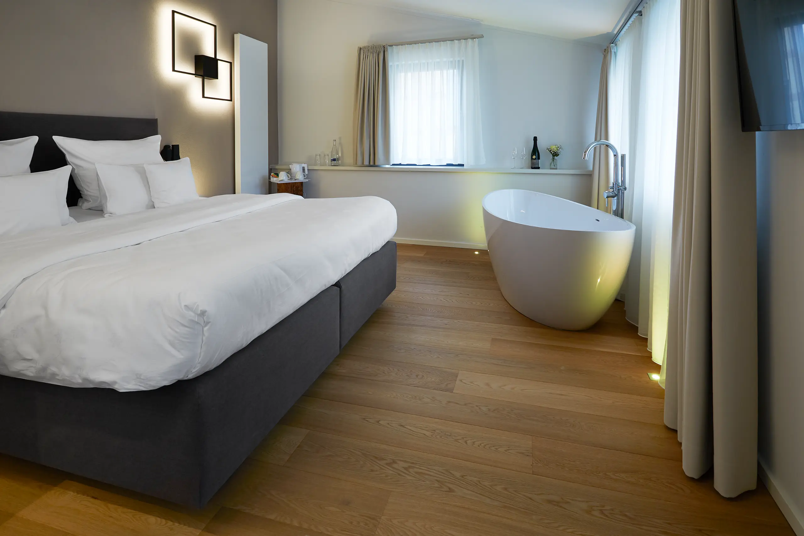 Honeymoon-Suite mit Doppelbett und freistehender Badewanne am Fenster