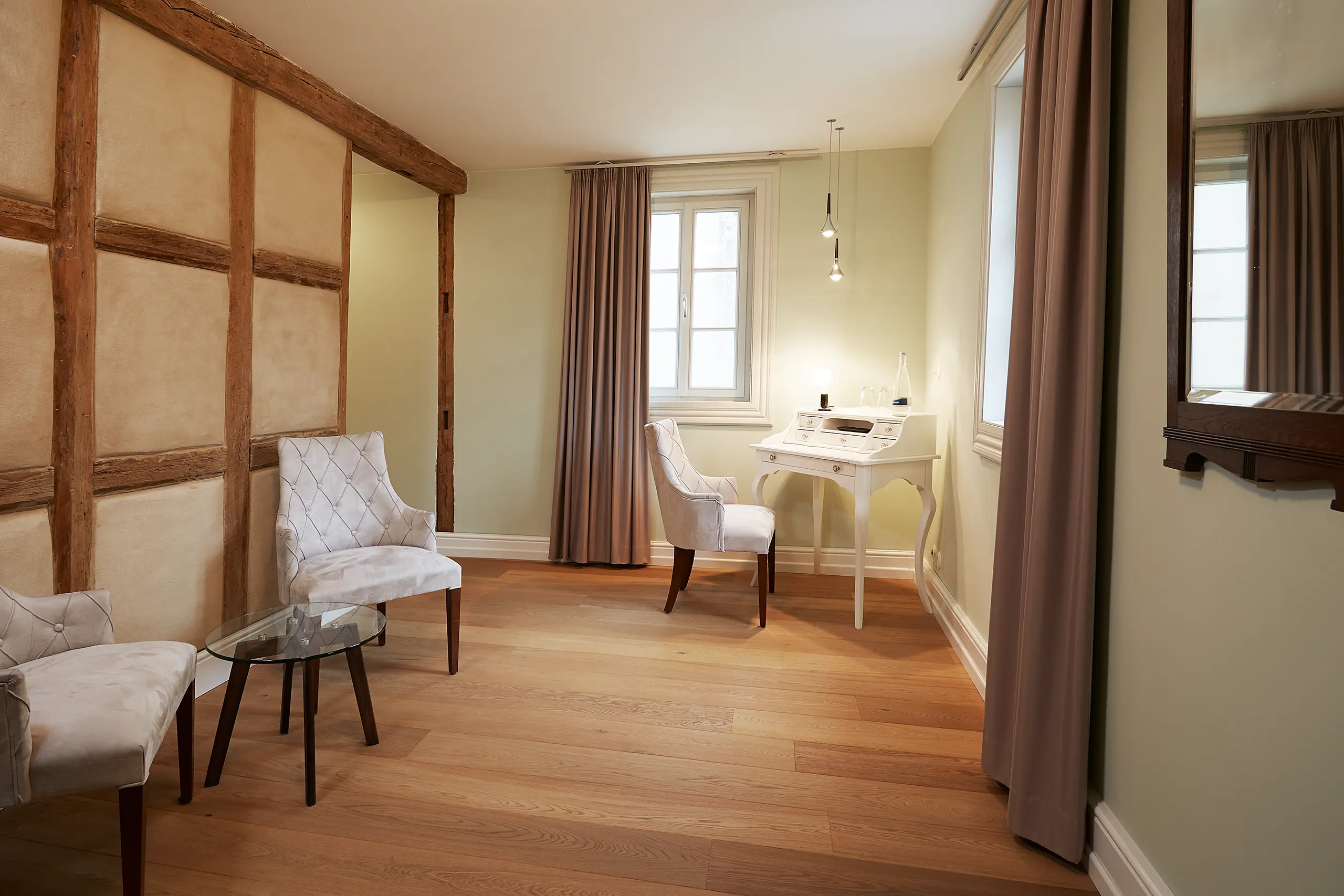 Komfort-Zimmer 6 im Fachwerkhaus mit Fachwerkwand, Sessel und Schreibtisch am Fenster
