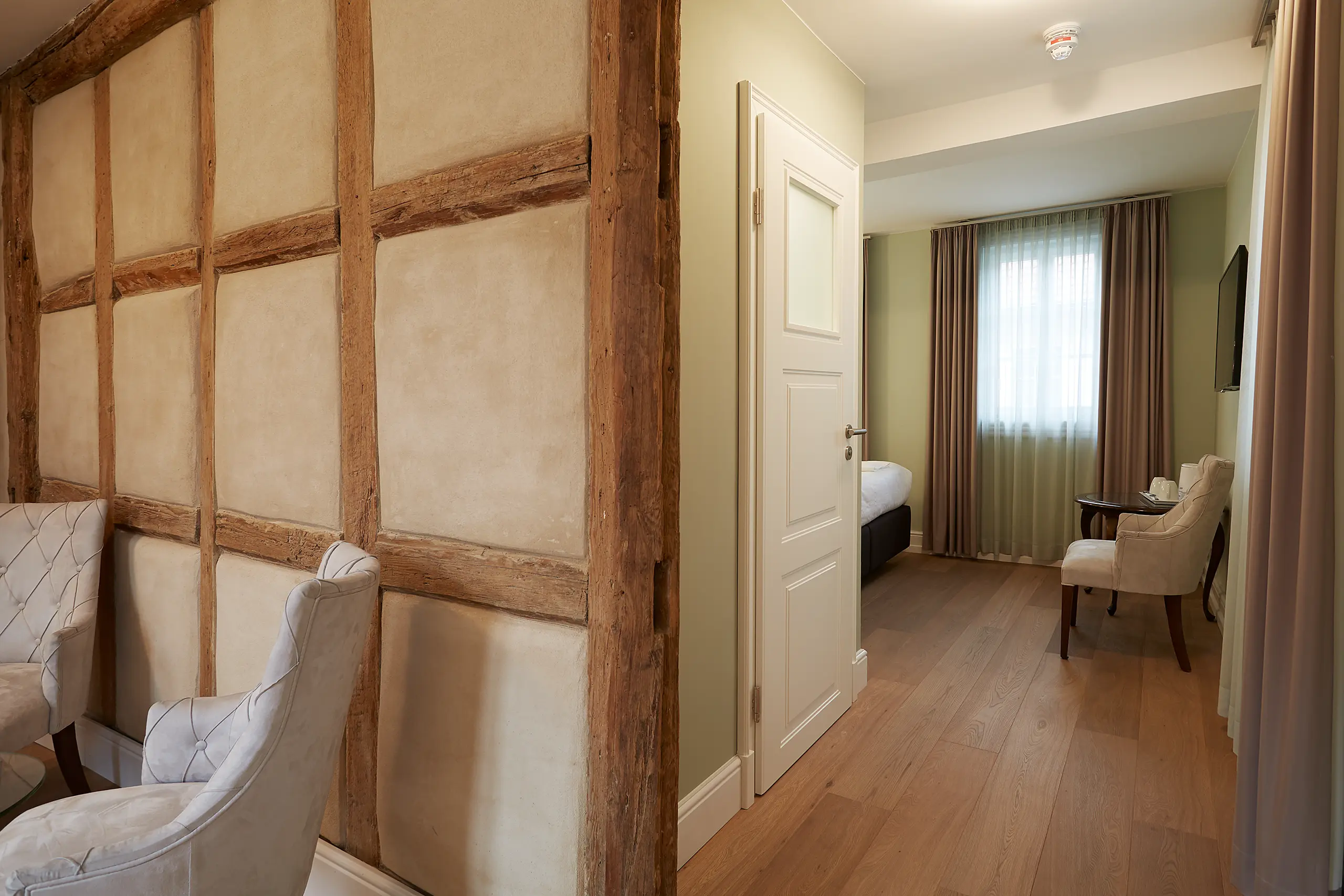 Sichtbare Fachwerkwand mit Lehmgefachen und weißem Sessel in Komfort-Zimmer 6