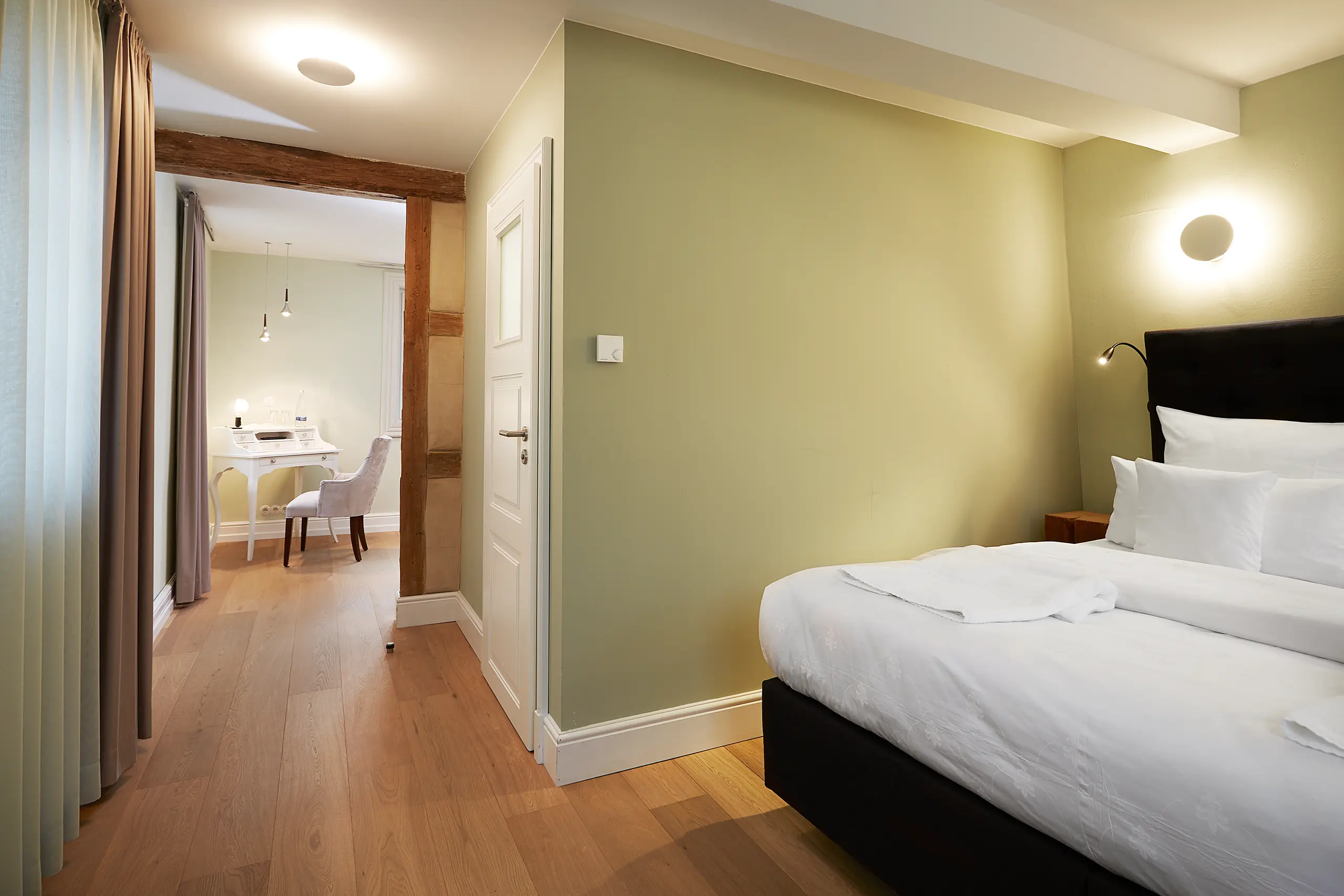 Komfort-Zimmer 6 im Fachwerkhaus mit Doppelbett, grünen Wänden und Blick in den Flur