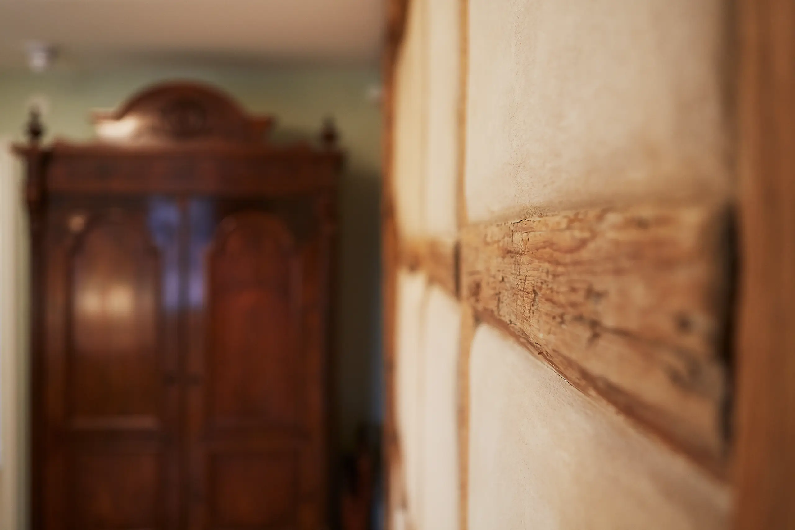 Detail alter Fachwerkbalken neben einem antiken Holzschrank in Zimmer 6