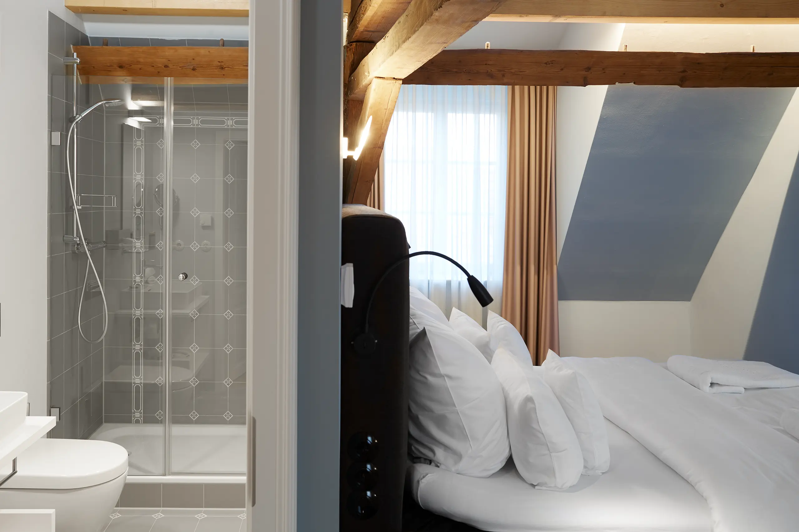 Komfort-Zimmer 9 im Fachwerkhaus mit Glasdusche neben dem Bett unter der Dachschräge