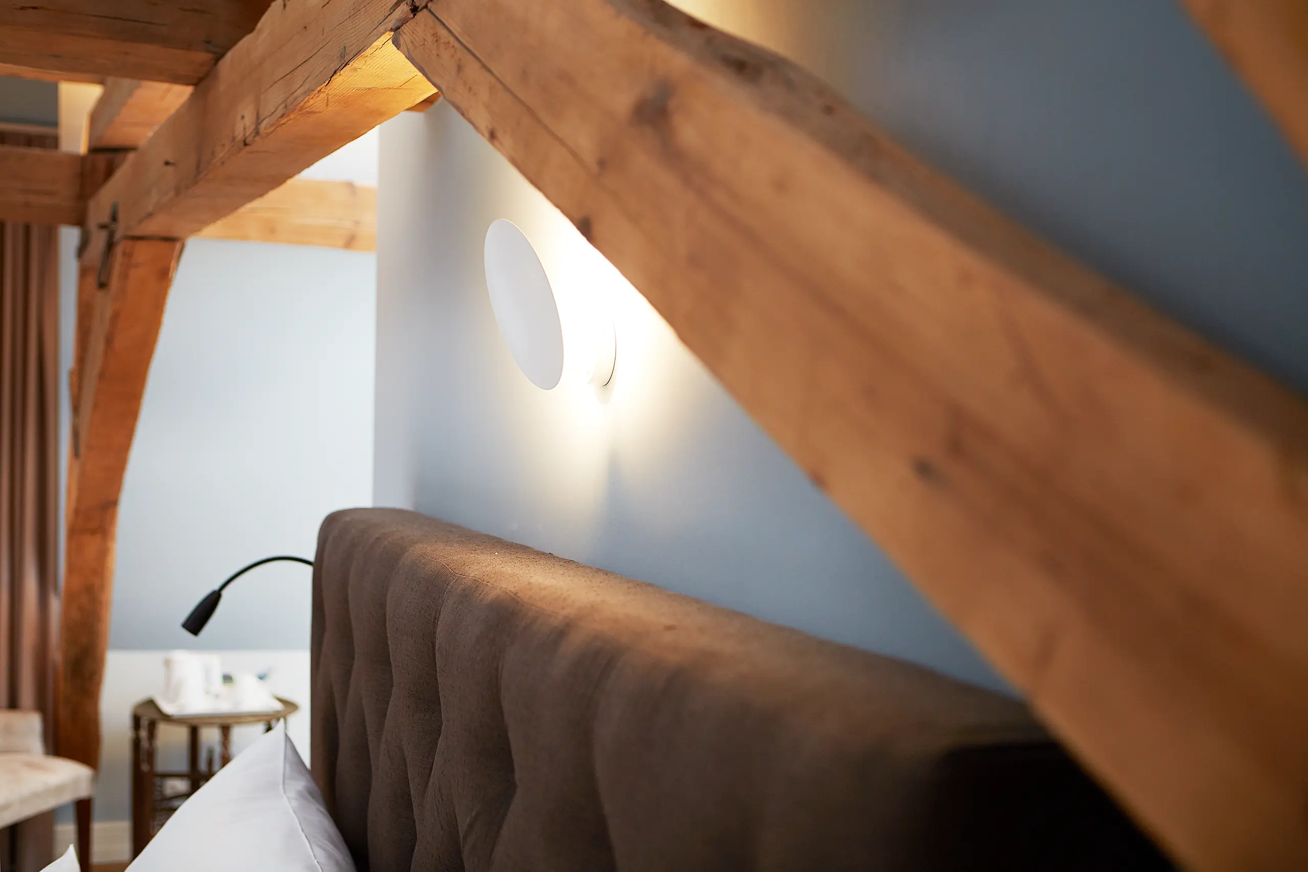 Kopfteil des Betts mit Wandleuchte und Holzbalken in Komfort-Zimmer 9 im Fachwerkhaus