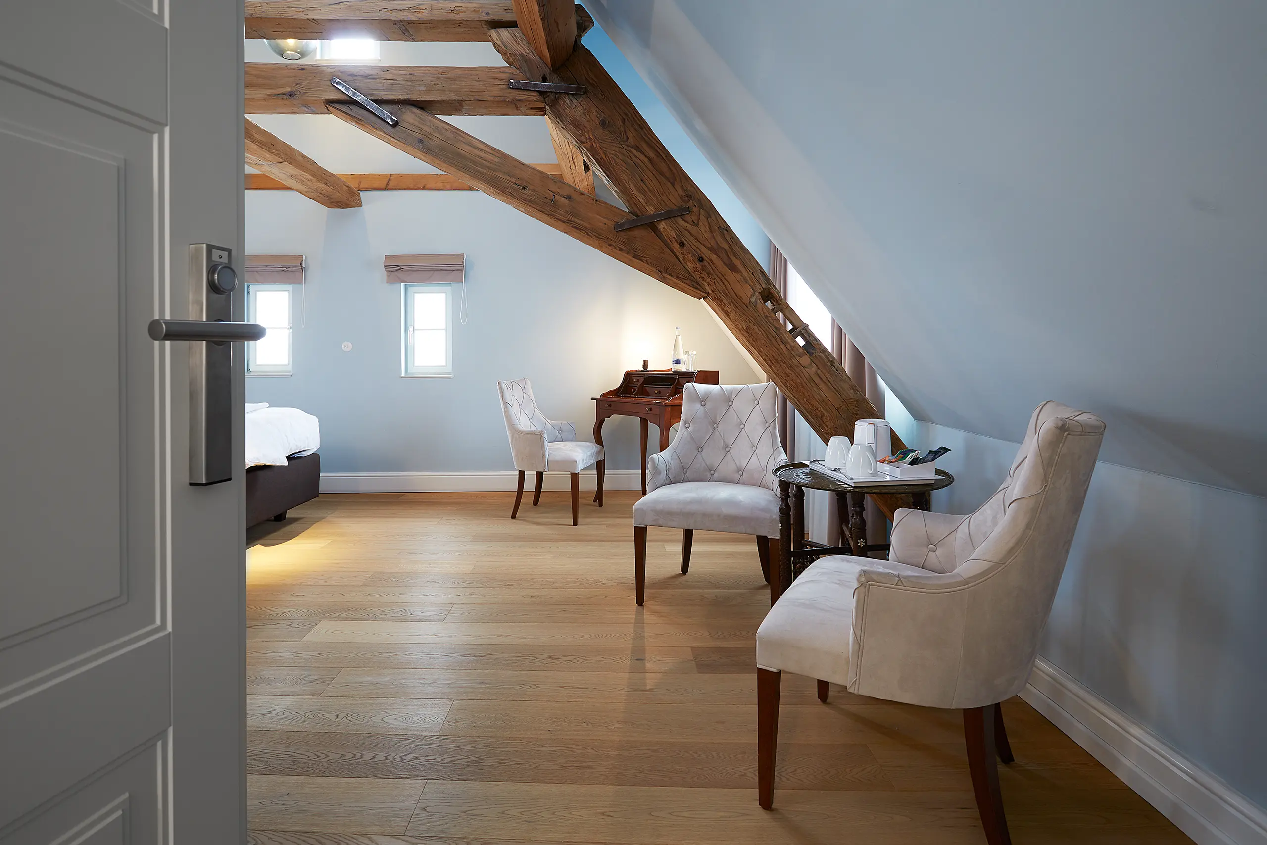 Blick durch die Tür auf Komfort-Zimmer 9 im Fachwerkhaus mit Sessel und Dachbalken