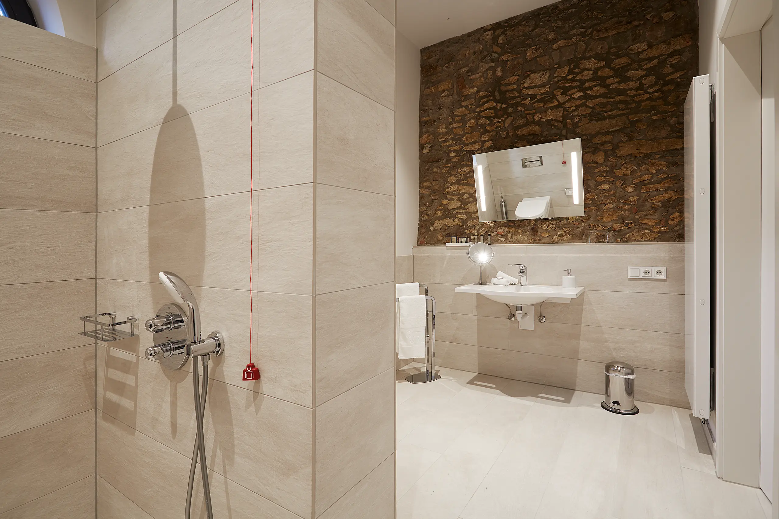 Barrierefreies Badezimmer mit bodengleicher Dusche und Natursteinwand in der Scheune - barrierefreies Hotelzimmer Rheinhessen