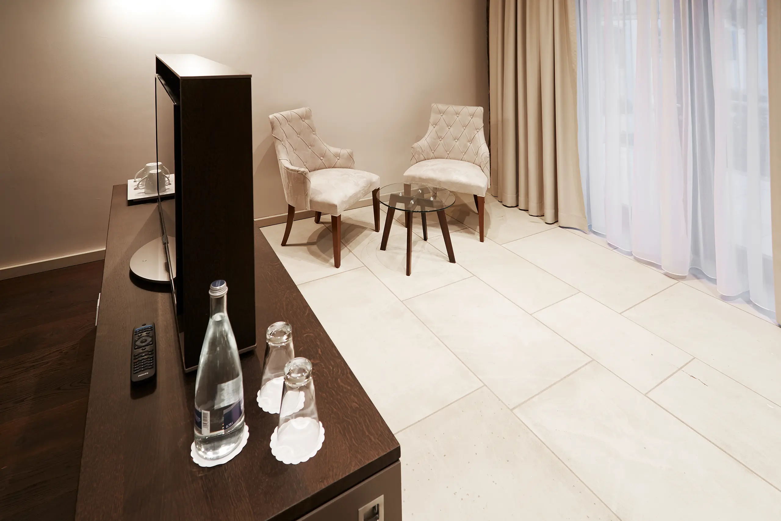 Sitzecke mit zwei Sesseln und Wasserkaraffe im Superior-Zimmer in der Scheune