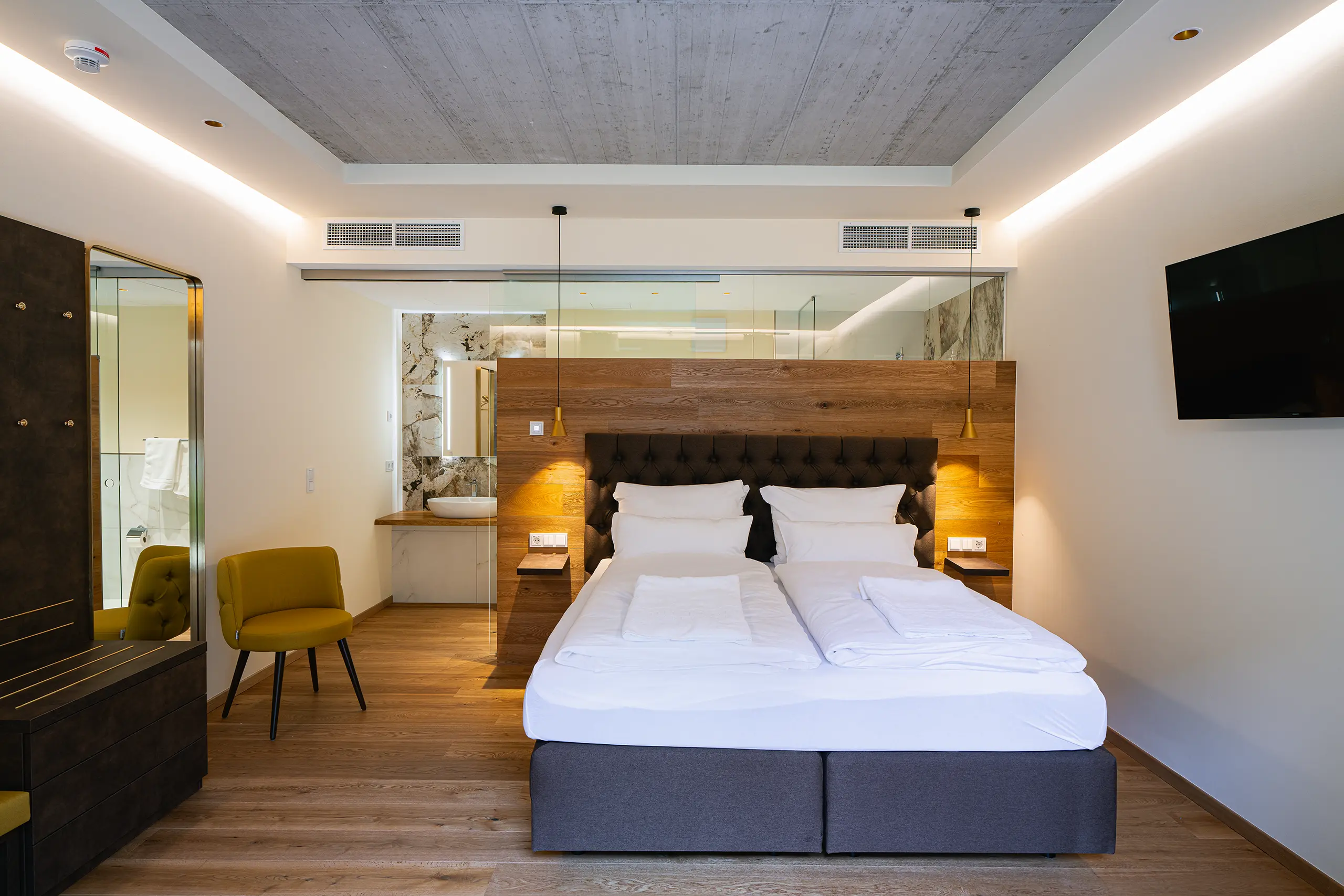 Superior-Zimmer im Neubau mit Doppelbett, indirekter Beleuchtung und gelbem Sessel