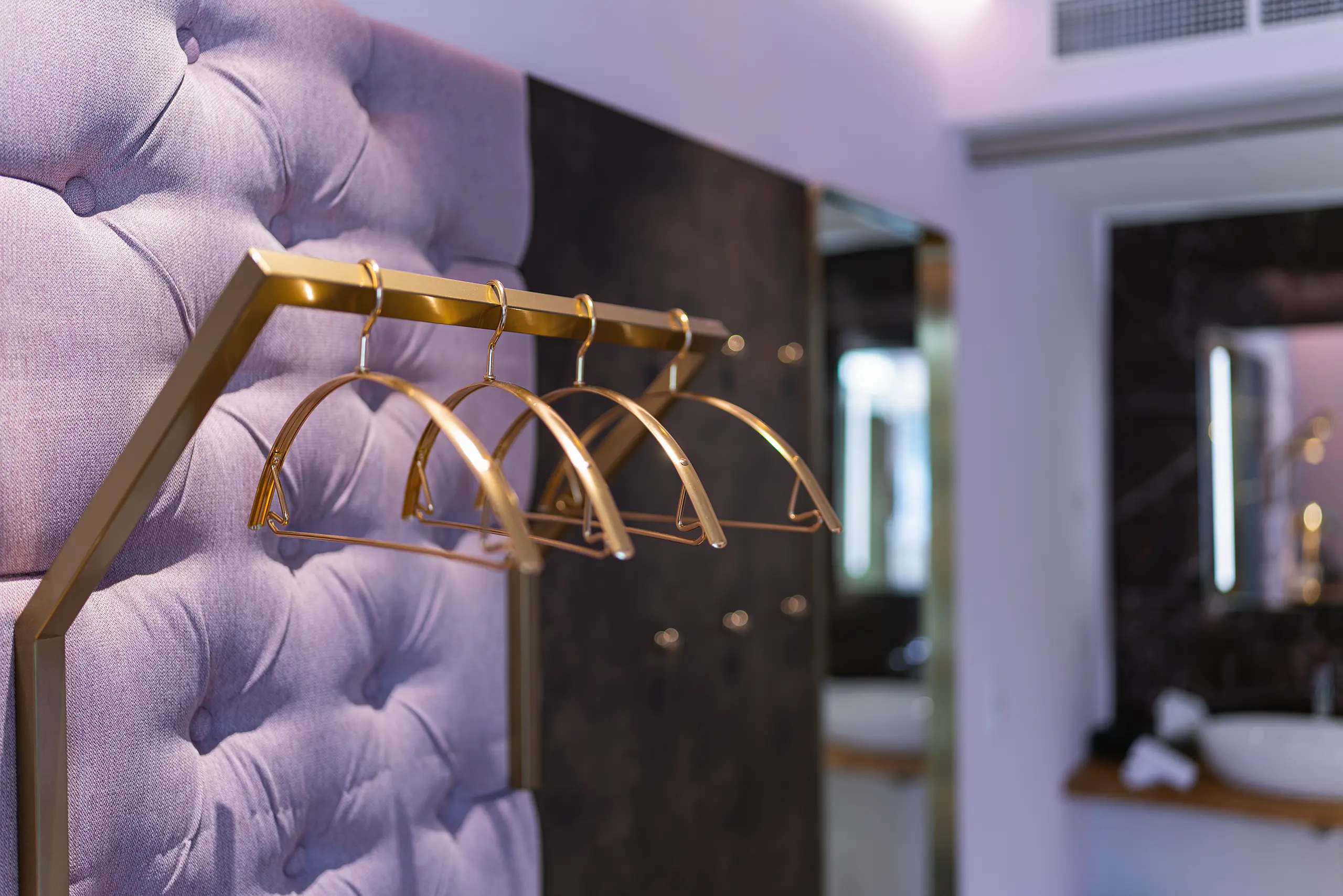 Goldene Kleiderhaken an gepolsterter Wand in Zimmer 26 im Neubau