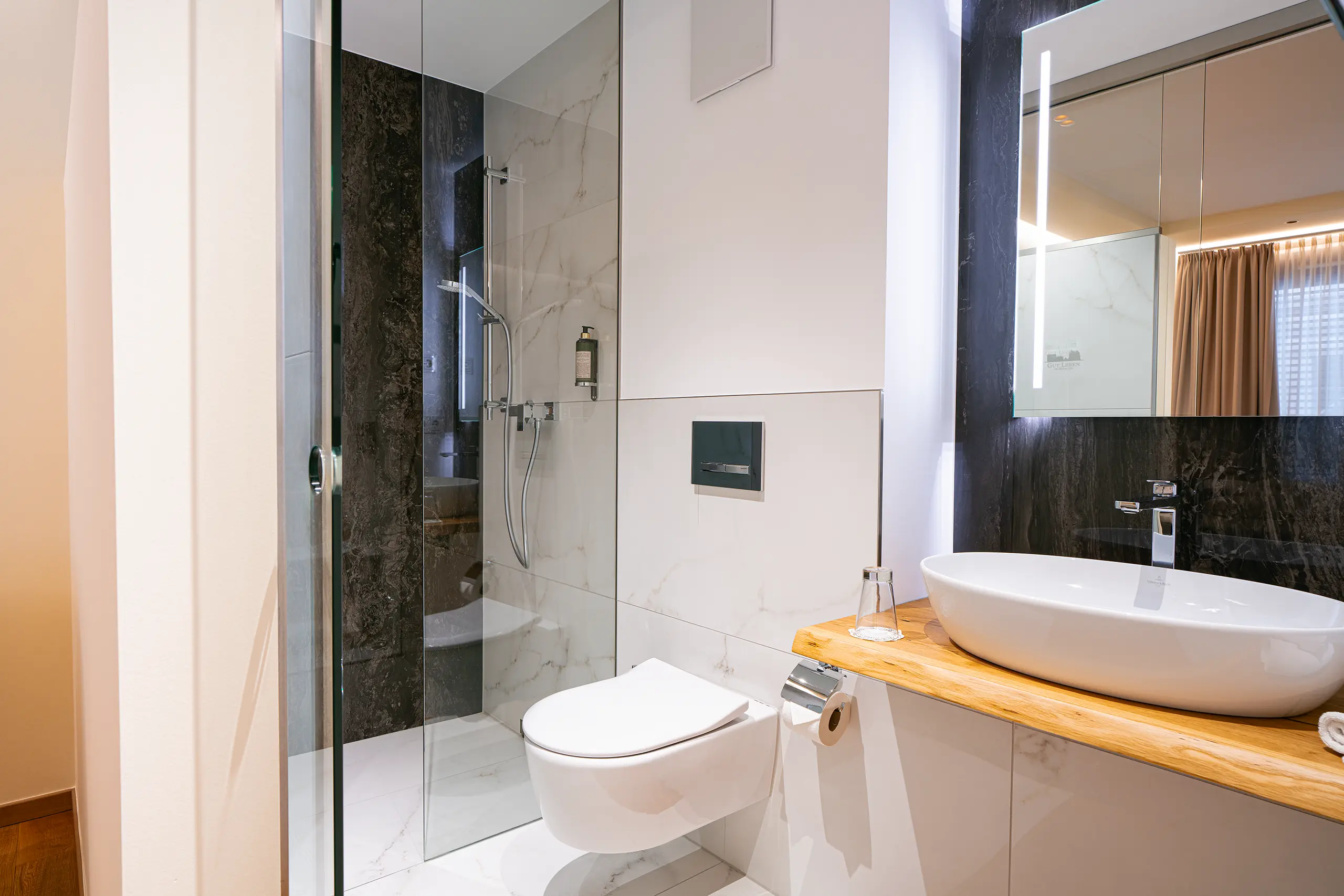 Badezimmer in Zimmer 32 im Neubau mit Waschbecken, Spiegel und Glasdusche