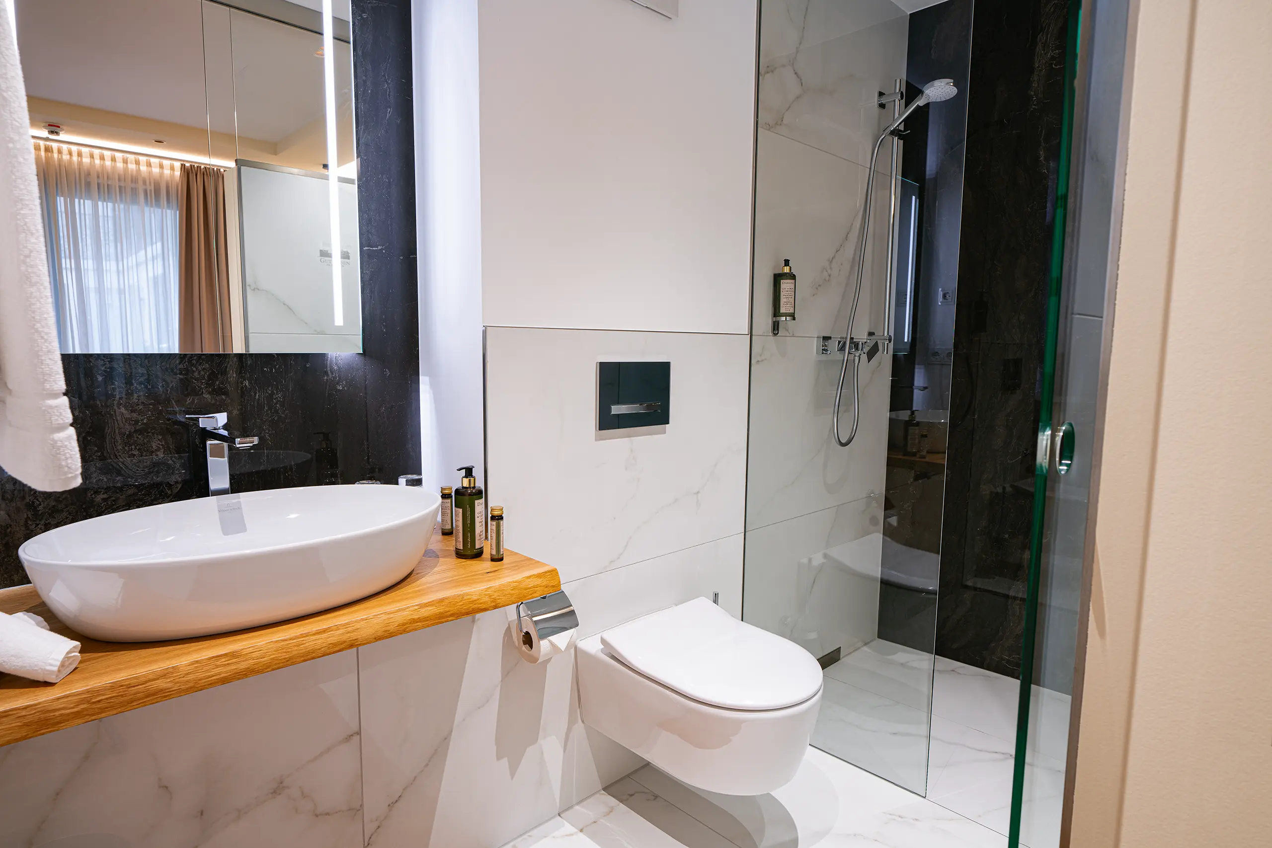 Badezimmer in Zimmer 33 im Neubau mit Waschbecken, WC und Glasdusche