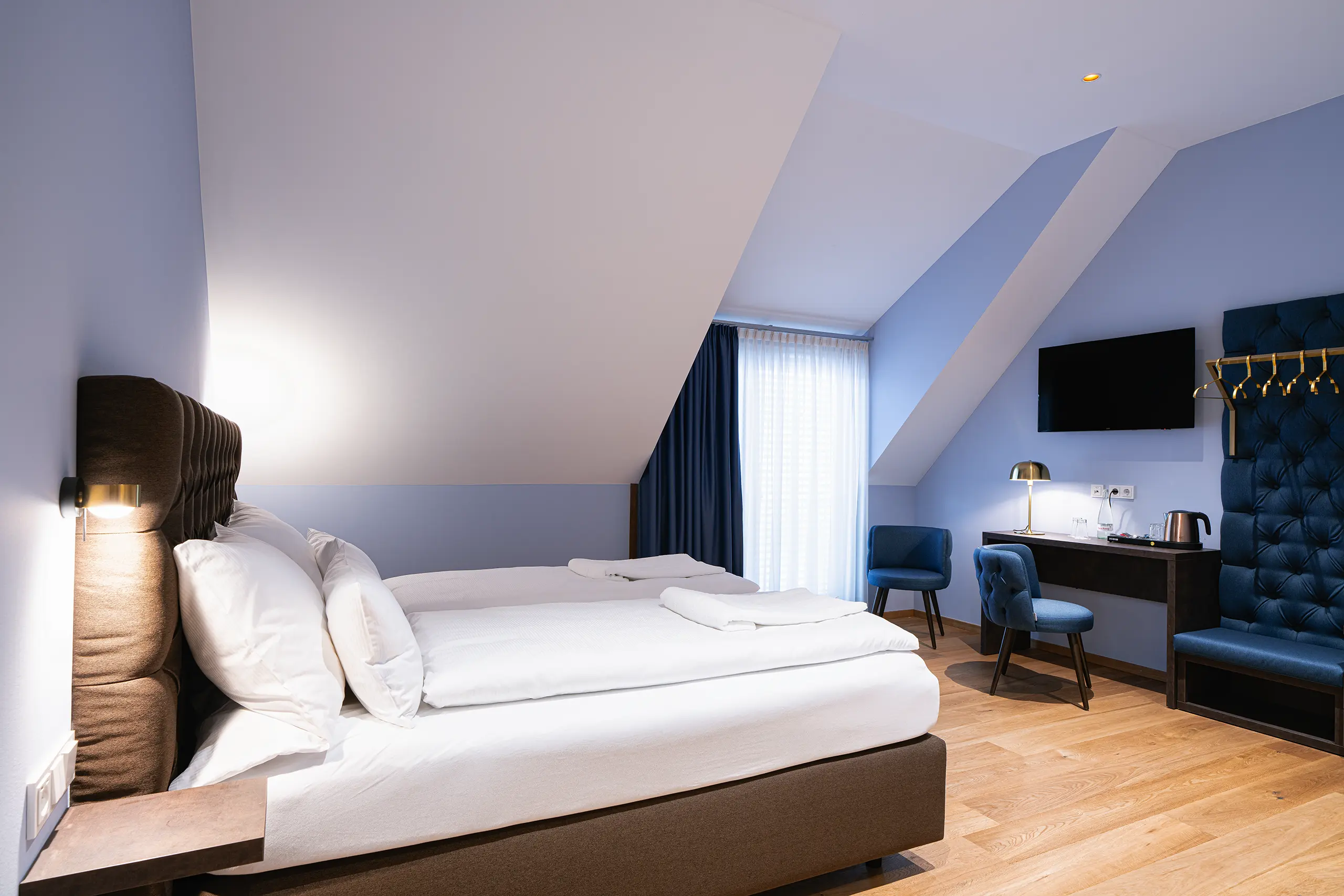 Superior-Zimmer 40 im Neubau unter der Dachschräge mit Doppelbett und blauen Sesseln
