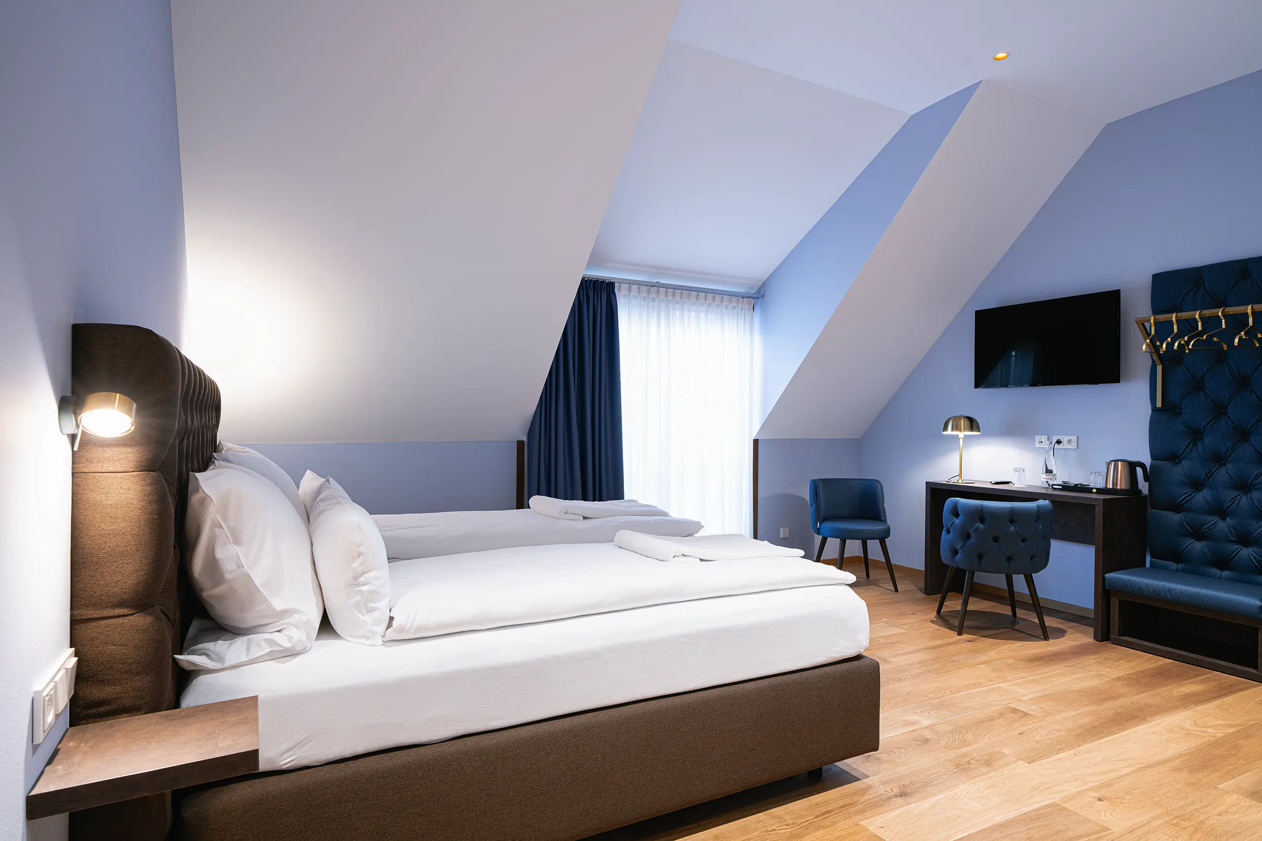 Superior-Zimmer 41 im Neubau unter der Dachschräge mit Doppelbett und blauem Sessel