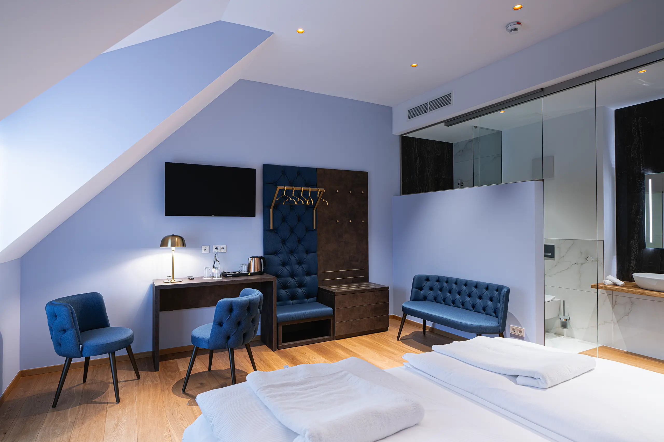 Superior-Zimmer im Neubau mit Doppelbett, blauen Sesseln und Schreibtisch unter der Dachschräge