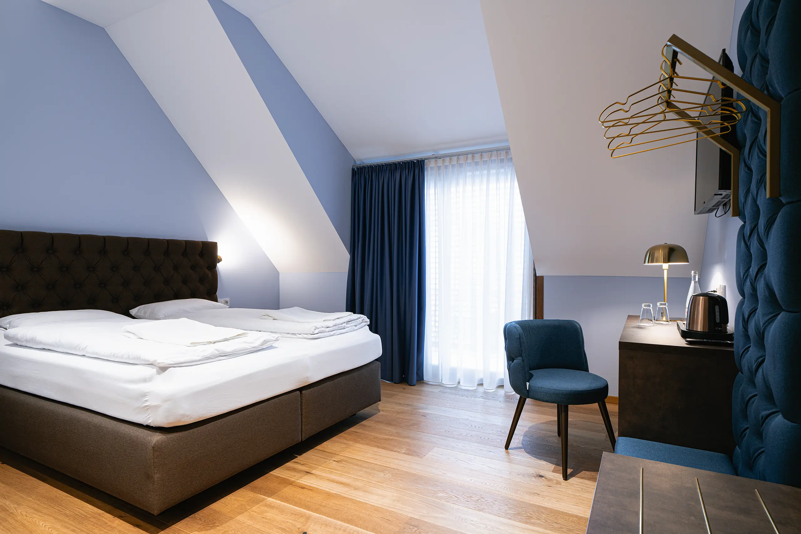 Superior-Zimmer 42 im Neubau unter der Dachschräge mit Doppelbett und blauem Sessel