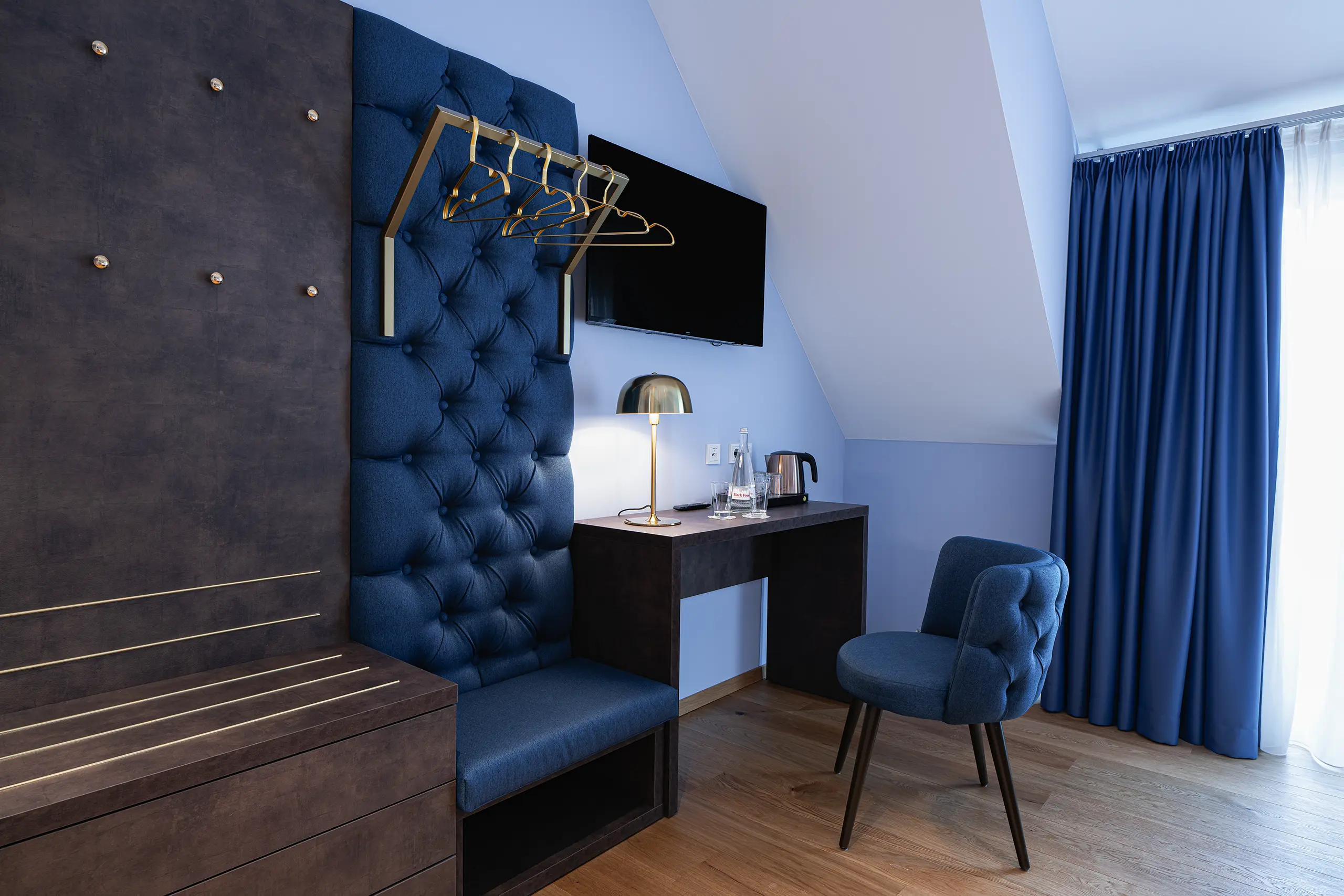 Superior-Zimmer 43 im Neubau mit Schreibtisch, blauem Stuhl und gepolsterter Wand