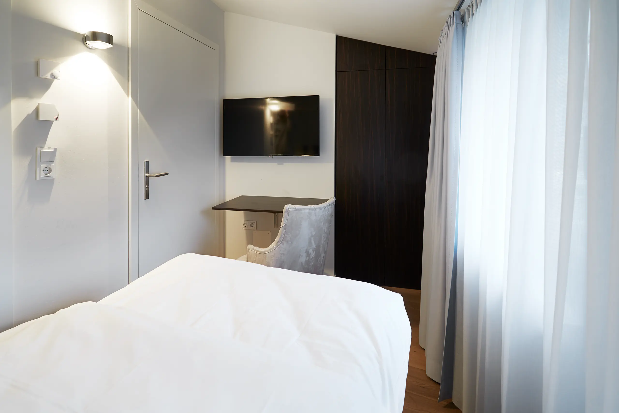 Einzelzimmer Standard in der Remise mit Bett, Schreibtisch, Vorhang und Bildschirm