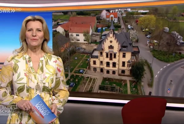 Moderatorin im SWR-Studio mit Luftbild des Schlösschens, Vorschaubild zum Fernsehbeitrag